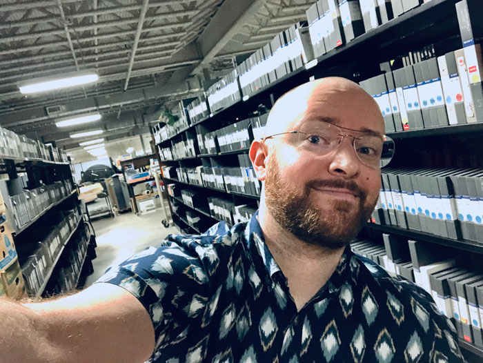 MSIS student Adam Hembree poses with donated collections in the basement of the Blount County Public Library, where he's doing a practicum this fall.