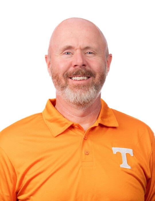 Scott Sikes wearing a UT orange polo shirt with a white power T on it.