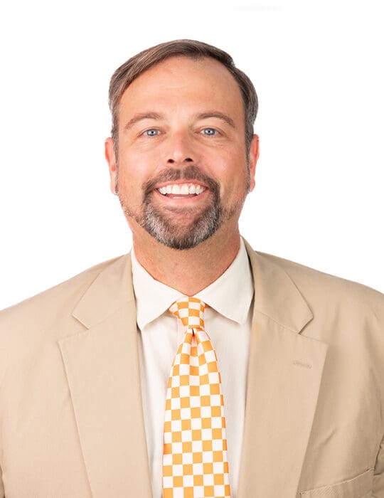 Professor Wade Bishop with an orange UT checkered tie, white shirt, and tan sports coat.